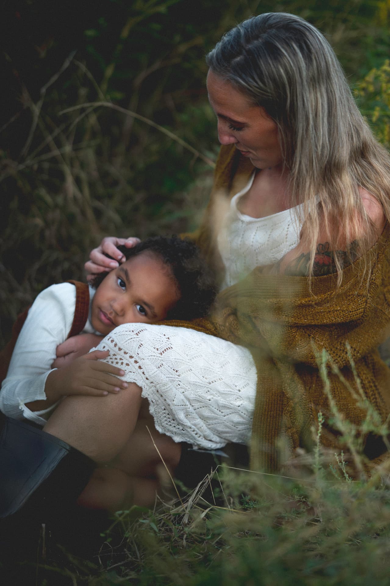 Mother in a mustard cardigan holding her young daughter close in tall Lowcountry grass